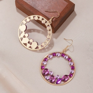 Détail de boucles d'oreilles bohèmes rondes avec pierres violettes sur tissu texturé