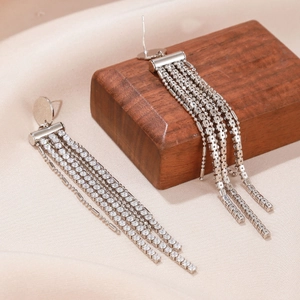 Close-up of luxury silver tassel earrings with sparkling rhinestones on satin fabric