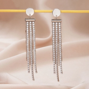 Detail of silver long tassel earrings featuring floral rhinestones on silk background