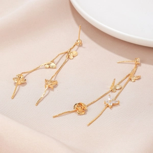 Macro detail of long tassel earrings with gold butterfly floral motifs and zircon inlay