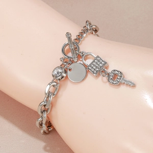 Detail of silver charm bracelet with pavé-set lock and key charms on an OT toggle clasp