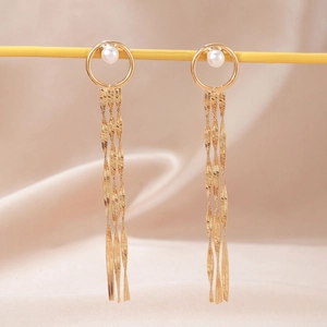 Macro shot of long gold tassels with snake chains and pearl accents on silk background