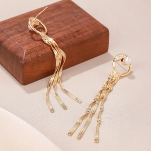 Detailed view of long gold tassel earrings with pearl studs and wavy metal plates