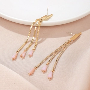 Macro view of long gold tassels with pink teardrop charms and cubic zirconia stones
