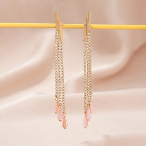 Detail of long gold tassel earrings with sparkling rhinestones and pink teardrop pendants