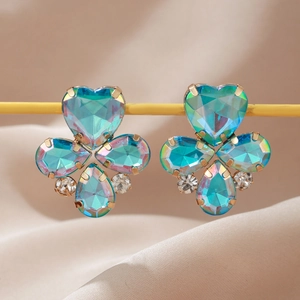 Macro de boucles d'oreilles trèfle iridescent avec cristaux bleu-vert et placage d'or