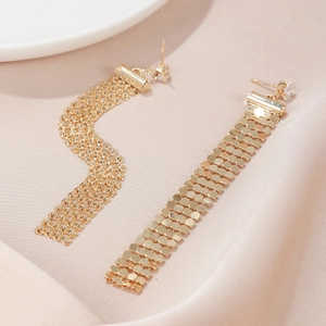 Close-up of elegant gold tassel earrings with rhinestone mesh and silk background