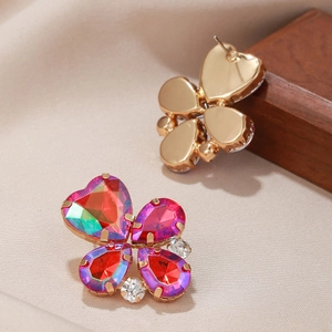 Détail de boucles d'oreilles trèfle rose rouge avec gemmes en cœur et base dorée