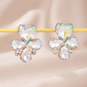 Vue macro de boucles d'oreilles trèfle iridescent en or rose sur de la soie rose