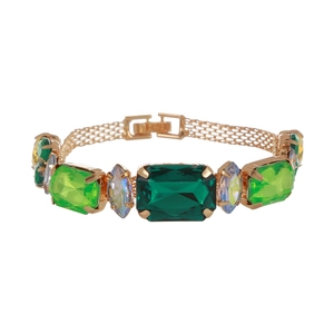 Gros plan d'un bracelet vintage doré orné d'émeraudes et de pierres précieuses