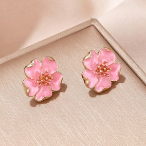 Élégantes boucles d'oreilles fleur de cerisier rose et or sur un coffret à bijoux en soie