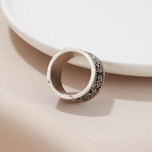 Vintage silver hollow wide ring with floral and bird relief patterns on a silk background
