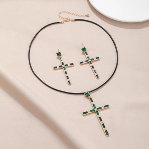 Parure de bijoux croix vintage avec pierres vertes, collier et boucles sur tissu beige