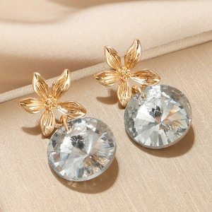 Elegant gold flower earrings with large clear faceted crystal pendants on silk fabric