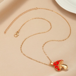 Close-up of golden mushroom pendant necklace with red enamel and pavé zircon details
