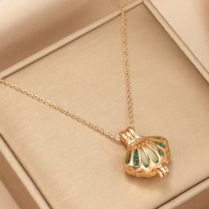 Detail of gold hollow shell pendant with luminous pearl and blue micro-inlaid stones