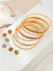 Detail of gold-tone bangles with hammered texture and glitter studs jewelry set
