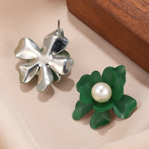 Deep green petal earrings with white pearl center on a natural wooden and silk background