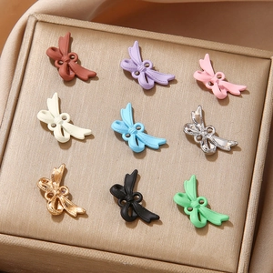 Bow-shaped alloy DIY jewelry pendants in nine pastel colors on a gold textured display