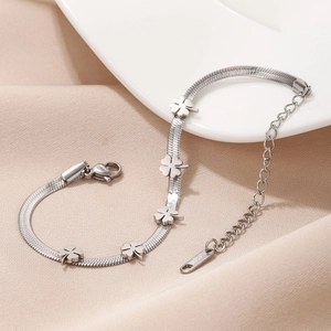 Titanium steel snake chain bracelet with five clover charms on elegant silk background