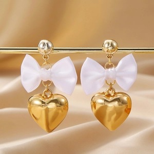 Élégantes boucles d'oreilles cœur doré avec nœuds en satin blanc sur soie champagne