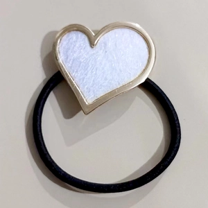 Minimalist elastic hair tie with white heart pendant and gold metal frame on gray background