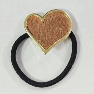 Close-up of heart-shaped hair tie with golden metal edges and brown faux fur texture