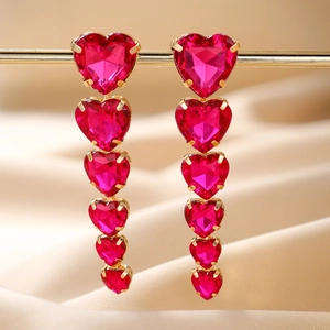 Detail of elegant gold-tone earrings featuring six cascading red heart-shaped crystals