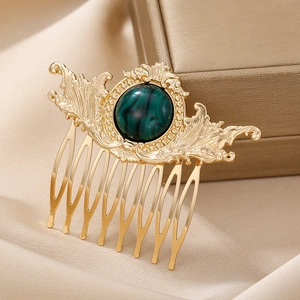 Detailed close-up of a vintage golden hair comb with green stone on satin background