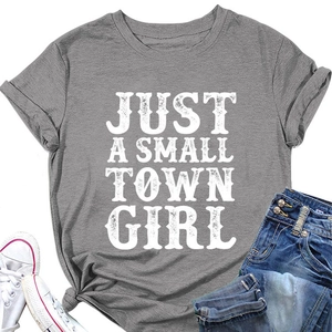 T-shirt gris avec imprimé 'JUST A SMALL TOWN GIRL' posé à plat avec jean denim