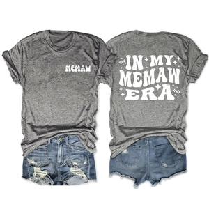 Flat lay of gray T-shirt with white In My Memaw Era prints and ripped denim shorts