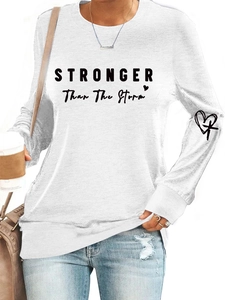 Close-up of Stronger Than The Storm print and heart cross detail on white sweatshirt