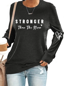 Detail of STRONGER letters and heart cross print on black long sleeve crewneck top