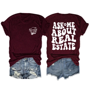 Detail of burgundy tee with Ask Me About Real Estate print and ripped denim shorts