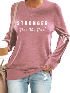 Detail of dusty pink sweatshirt featuring Stronger Than The Storm text and heart patterns