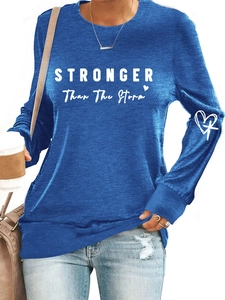 Detail of the white STRONGER than the Storm print and cross logo on a navy blue sweatshirt