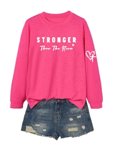 Detail of pink long sleeve sweatshirt with STRONGER lettering and ripped denim shorts