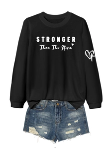 Flat lay of black sweatshirt with 'Stronger Than The Storm' text and ripped denim shorts