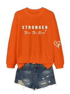 Detail of STRONGER text on orange crewneck sweatshirt with distressed denim shorts