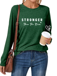 Detail of dark green crewneck shirt featuring white STRONGER Than The Storm print