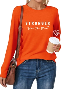 Detail of Stronger Than The Storm print on an orange crewneck long sleeve t-shirt