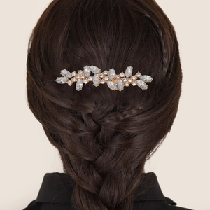 Peigne à cheveux doré avec strass et perles sur une tresse de cheveux châtains
