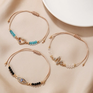Three-piece evil eye and heartbeat charm braided rope bracelets on silk background