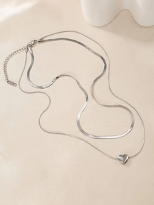 Détail d'un collier double épaisseur argenté avec pendentif cœur sur tissu