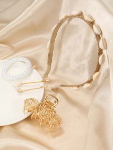 Détail d'un ensemble d'accessoires de cheveux coquillage doré sur du satin champagne