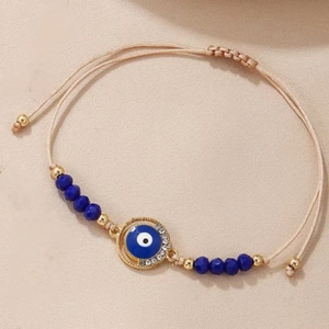 Detail of hand-woven Evil Eye bracelet with navy beads and gold adjustable sliders