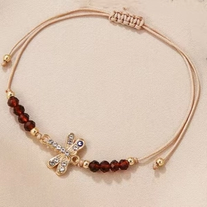 Detailed shot of beige woven dragonfly bracelet with crystals and evil eye charm
