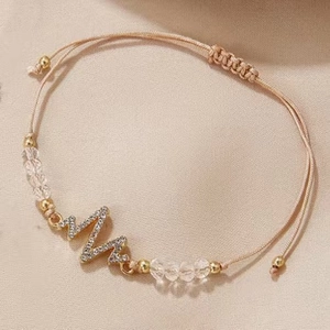 Detailed macro view of woven bracelet featuring an EKG heartbeat charm with crystals