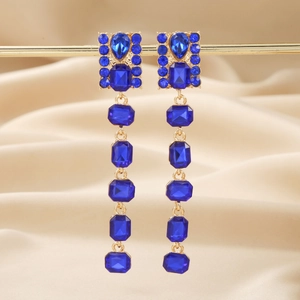Elegant gold drop earrings with blue rhinestones displayed on champagne silk fabric