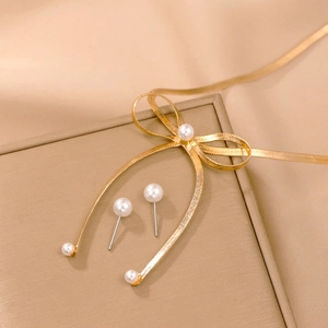Elegantes Set aus goldener Schleifen-Perlenkette und Ohrsteckern auf goldenem Satin-Hintergrund